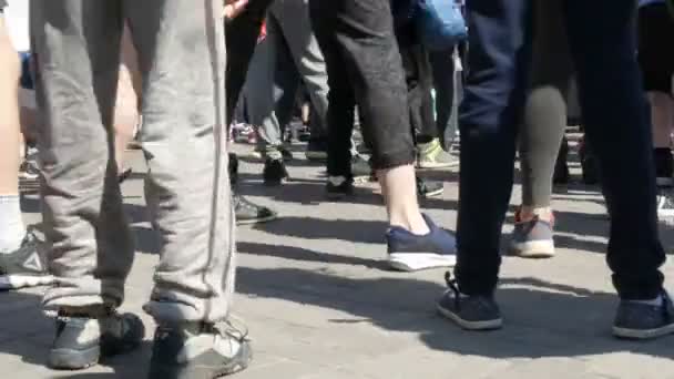 21 de abril de 2018 Kamenskoye, Ucrânia: grande número de pessoas pernas fazem um aquecimento antes da corrida de maratona. Saltos e agachamentos de um grande número de pessoas na praça — Vídeo de Stock