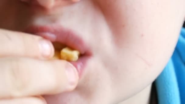 Vista cercana de la boca de los adolescentes. Un chico con apetito está comiendo papas fritas en un restaurante de comida rápida. — Vídeos de Stock