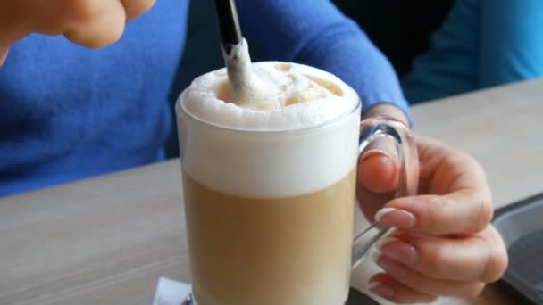 Vrouwelijke handen zijn roeren de lucht schuim uit de latte met rietje — Stockvideo