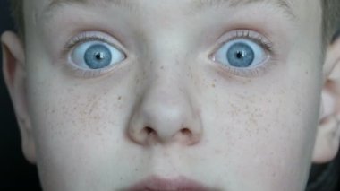 Komik neşeli mavi gözlü çocuk kameraya şaşırır çilli çocuk ile