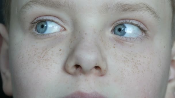 Zamyšlenou tváři modrýma očima dospívajícího chlapce s pihy zblízka — Stock video