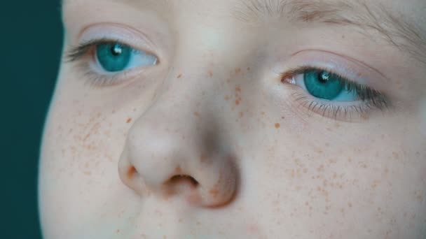 Extraordinariamente hermosos ojos turquesas de adolescente con pecas en su cara vista de cerca. Vista seria del niño — Vídeos de Stock