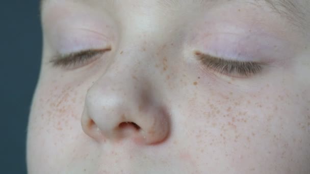 Blaue Augen eines blonden Teenagers mit roten Sommersprossen im Gesicht und langen weißen Wimpern, der in die Kamera blickt — Stockvideo