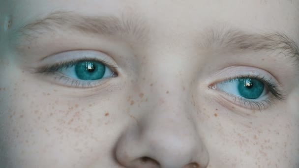 Zamyšlenou tváři modrýma očima dospívajícího chlapce s pihy zblízka — Stock video
