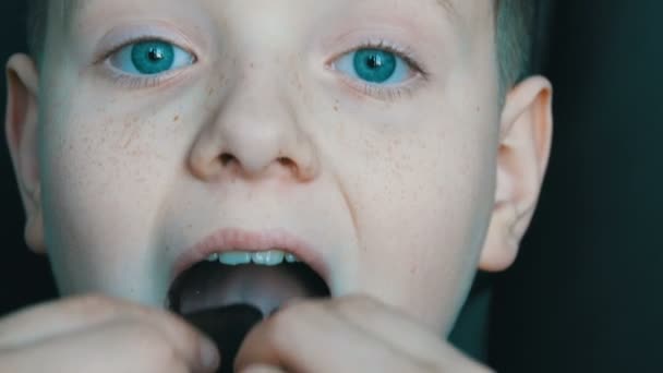 Pihovatý chlapec blond dospívající jíst čokoládové bonbóny zblízka — Stock video