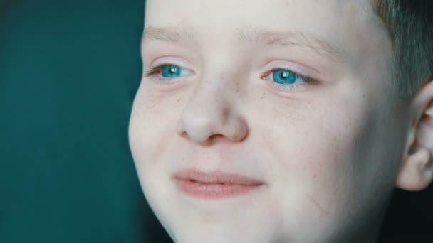Heureux yeux turquoise de garçon blond adolescent avec des taches de rousseur sur le visage et de longs cils blancs qui regarde loin — Video