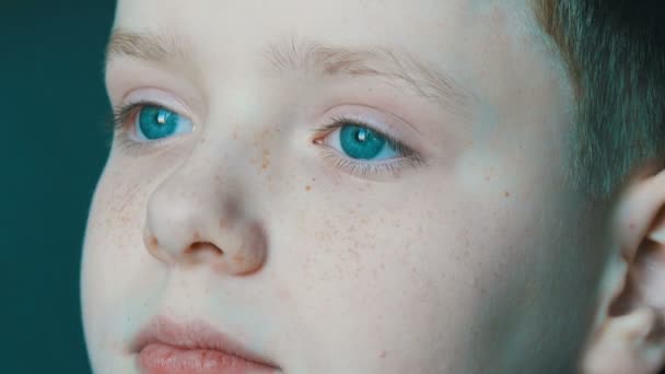 非常美丽的青绿色的眼睛, 在他的脸上有雀斑的年轻男孩密切的看法。男孩的严肃的看法 — 图库视频影像