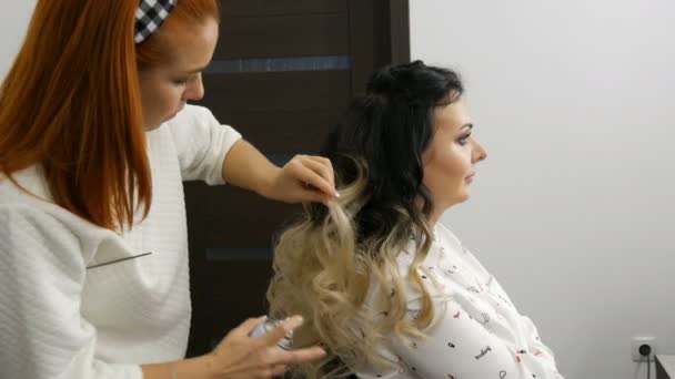 20 сентября 2019 - Каменское, Украина: Профессиональный стилист-парикмахер делает стилизацию с лаком для волос для красивой молодой женщины с длинными волосами, окрашенными в комбинированную технику в студии красоты — стоковое видео