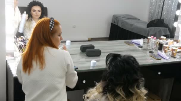 20 Eylül 2019 - Kamenskoye, Ukrayna: Profesyonel kuaför, güzellik stüdyosunda ombre tekniği ile boyalı uzun saçlı güzel bir genç kadın için saç spreyi ile saç stili yapıyor — Stok video