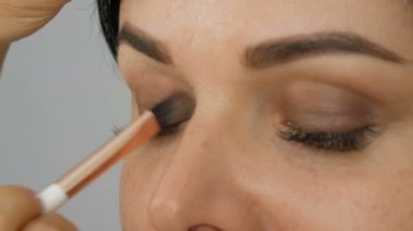 Göz makyajı, özel fırça ve gri göz farı. Mavi gözlü, uzun kirpikli.