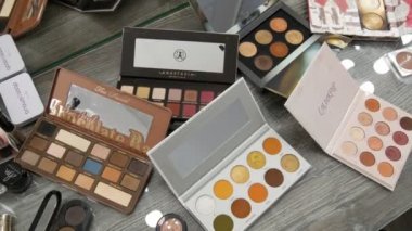 20 Eylül 2019 - Kamenskoye, Ukrayna: Güzellik stüdyosundaki bir masanın üzerinde çeşitli makyaj kozmetik paletleri. Göz farı, makyaj temeli, ruj.