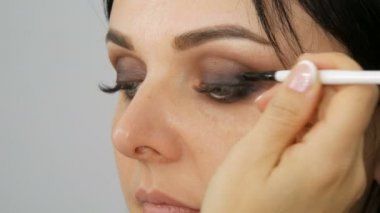 Göz makyajı, özel fırça ve gri göz farı. Mavi gözlü, uzun kirpikli.