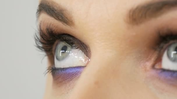 Hermosa noche costosa elegante maquillaje ojos ahumados de gris inusual y azul sombra de ojos. Hermosos ojos azules femeninos vista de cerca — Vídeo de stock