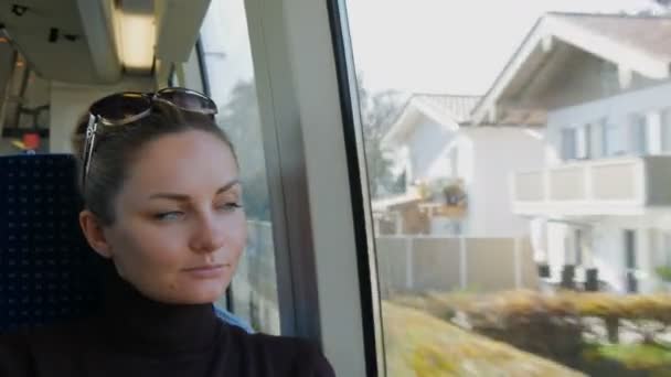 Mulher bonita com olhos verdes e longas pestanas pretas cavalga no trem olhando sonhadamente e pensadamente pela janela — Vídeo de Stock