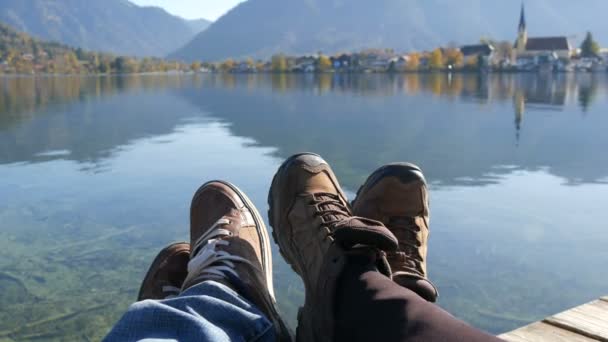 Tegernsee, Duitsland - 26 oktober 2019: Reizigers koppelen wandelschoenen op berg bij de Tegernsee op de achtergrond van de kerk. Man en vrouw familie trekkingschoenen. — Stockvideo