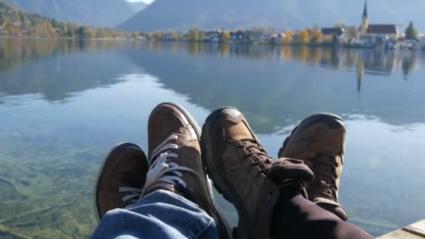 Tegernsee, Německo - 26. října 2019: Poutníci pár turistických bot na horách u jezera Tegernsee na pozadí kostela. Muž a žena rodina trekking boty. — Stock video