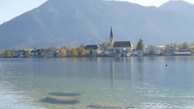 Tegernsee Gölü kıyısındaki Bavyera Alpleri 'nin arka planında canlı bir yerde eski güzel bir kilise.