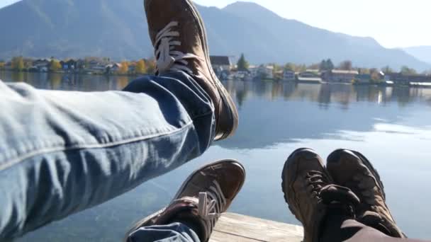 Tegernsee, Duitsland - 26 oktober 2019: Reizigers koppelen wandelschoenen op berg bij de Tegernsee op de achtergrond van de kerk. Man en vrouw familie trekkingschoenen. — Stockvideo