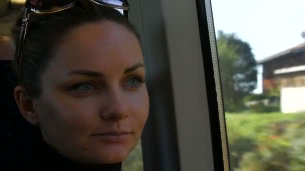 Nahaufnahme Porträt der schönen jungen Frau mit grünen Augen und langen schwarzen Wimpern fährt im Zug und schaut verträumt und nachdenklich aus dem Fenster. Außenfenster ist buntes Herbstlaub. — Stockvideo