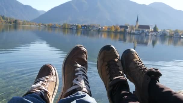 Tegernsee, Duitsland - 26 oktober 2019: Reizigers koppelen wandelschoenen op berg bij de Tegernsee op de achtergrond van de kerk. Man en vrouw familie trekkingschoenen. — Stockvideo