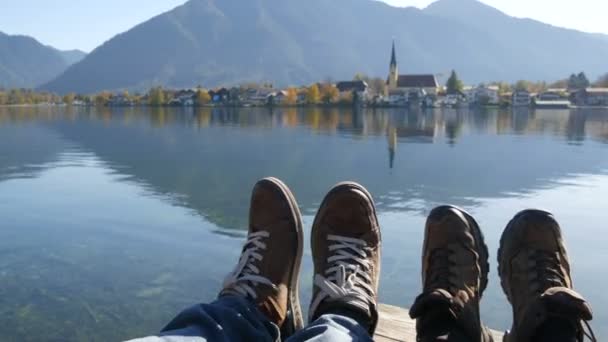 Tegernsee, Duitsland - 26 oktober 2019: Reizigers koppelen wandelschoenen op berg bij de Tegernsee op de achtergrond van de kerk. Man en vrouw familie trekkingschoenen. — Stockvideo