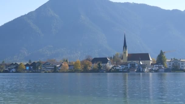 Schöne alte Kirche an lebendigem Ort vor dem Hintergrund der bayerischen Alpen am Ufer des Tegernsees — Stockvideo