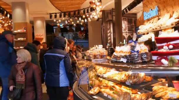 Mnichov, Německo - 2. prosince 2018: Dav lidí stojí ve frontě v pekárně. Velké množství pečiva sendviče, hamburgery, preclíky na pultu — Stock video