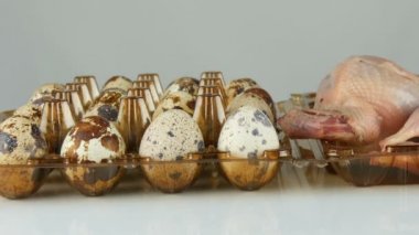 Beyaz arka planda bıldırcın yumurtalarının yanındaki plastik kahverengi tepside taze bıldırcın eti.