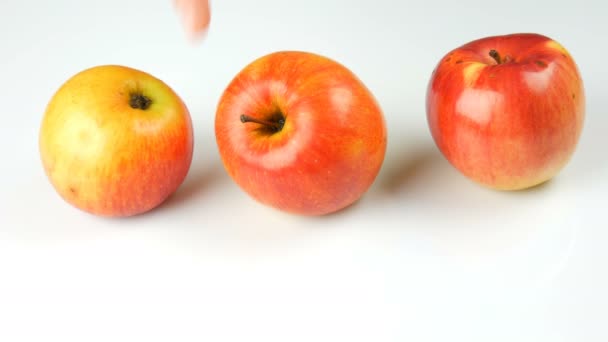 Female hand takes ripe juicy and fresh apple and puts ripened rotten spoiled apples on a white background. — Stock Video