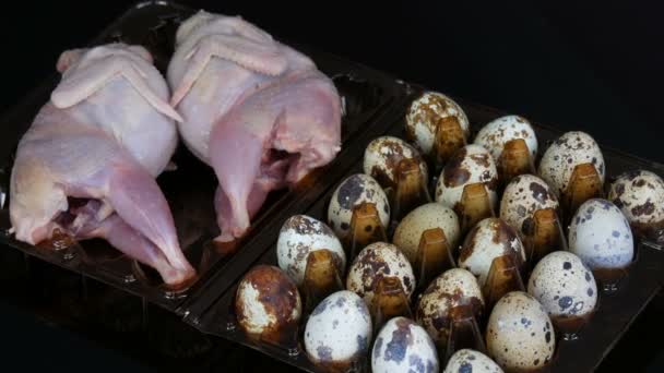 Fresh meat of quail in a plastic brown tray next to the quail eggs on black background — Stock Video