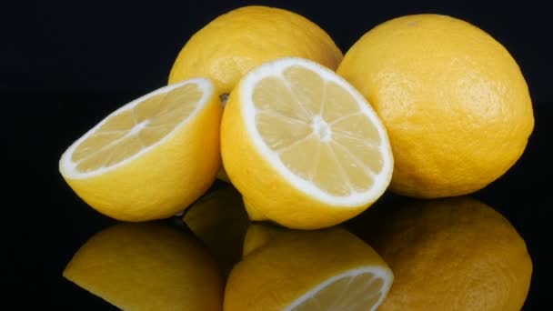 Зрізати свіжий соковитий жовтий лимон на чорному фоні обертається — стокове відео