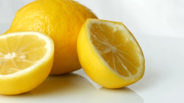 Спелый свежий сочный желтый лимон на белом фоне. Женская рука берет спелый лимон — стоковое видео