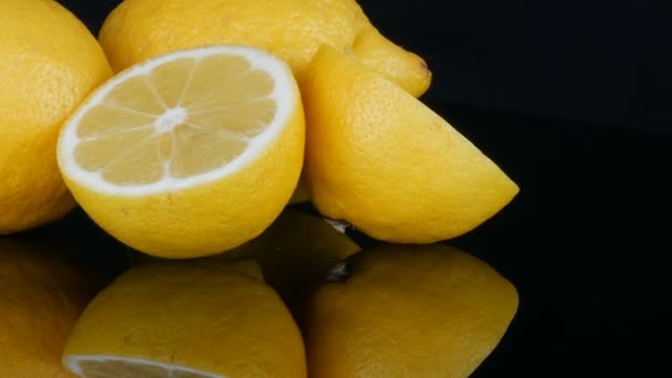 Reife frische saftige gelbe Zitrone auf schwarzem Hintergrund drehen — Stockvideo