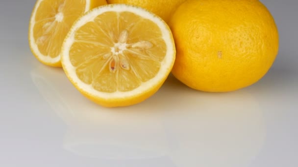 Зрізати свіжий соковитий жовтий лимон на білому тлі обертається — стокове відео