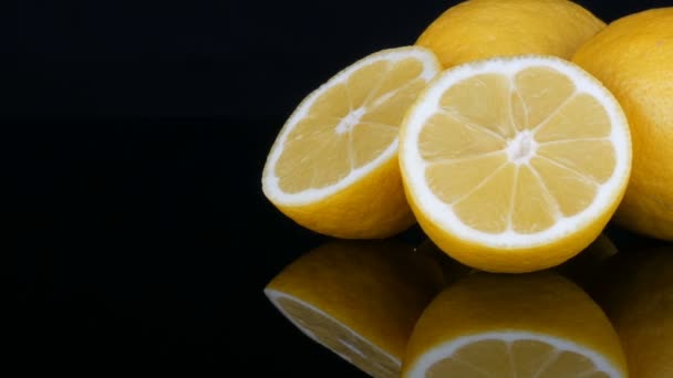 Спелый свежий сочный желтый лимон на черном фоне — стоковое видео