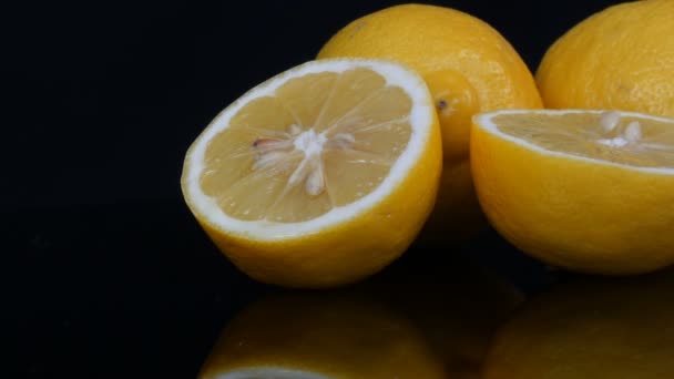 Reife frische saftige gelbe Zitrone auf schwarzem Hintergrund drehen — Stockvideo