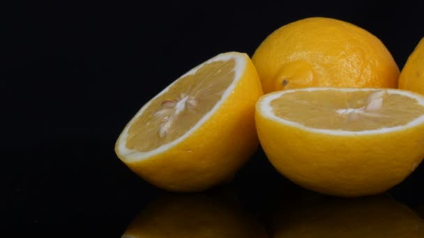 Спелый свежий сочный желтый лимон на черном фоне — стоковое видео