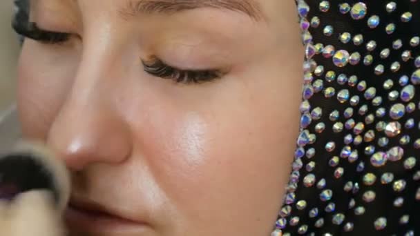 Le point culminant mélangeable avec un pinceau professionnel est appliqué sur le visage du modèle en gros plan. Jeune fille modèle avec de beaux yeux bruns dans le studio. Maquillage professionnel du maquilleur de haute couture — Video