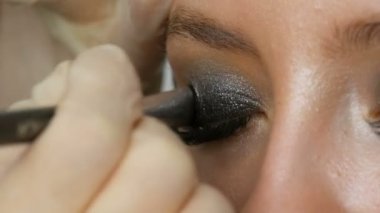 Makyaj sanatçısı özel fırça gri göz farı, gözler ve kız kirpik görünümü yakın yardımıyla modelleri dumanlı gözleri yapar. Profesyonel yüksek moda.