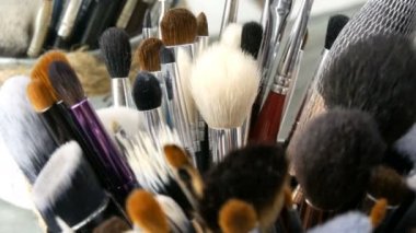Giyinme odasında masada makyaj için profesyonel Fırçalar ayarlayın. Moda endüstrisi. Sahne arkasında yüksek moda gösterisi. Makyaj sanatçısı bir fırça alır.