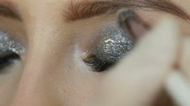 Makyaj sanatçısı özel gri göz farı, gözler ve kız kirpik görünümü yakın yardımıyla modelleri dumanlı gözleri yapar. Profesyonel yüksek moda.