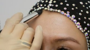 Profesyonel fırça ile blendable vurgu modeli yakın yukarı yüzüne uygulanır. Stüdyoda güzel kahverengi gözleri ile genç kız modeli. Profesyonel makyaj yüksek moda makyaj sanatçısı