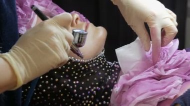 Profesyonel yüksek moda. Stilist bir hava fırçası ve boyalar yardımıyla giysiler üzerinde bir modelin bir görüntü oluşturur.
