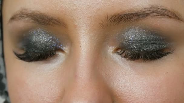 Makeup artist rende modelli occhi fumosi con l'aiuto di speciali pennello ombretto grigio, occhi e ciglia di ragazza vista da vicino. Alta moda professionale . — Video Stock