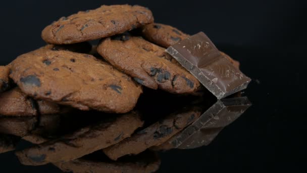 Schokoladenkekse und Schokoladenstücke auf stylischem schwarzen Hintergrund und Spiegeloberfläche — Stockvideo