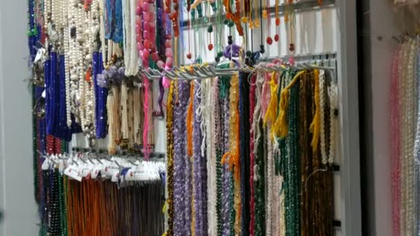 Istanbul, Turkey, June 11 - 2019: Multi-colored beads from various natural stones hang in jewelry store in Istanbul. Colorful beads necklaces fashionable womens statement jewelry — ストック動画