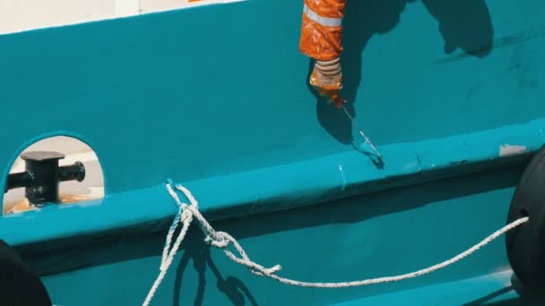 Ręka marynarza malującego farbą z rolkową rufą statku lub łodzią z niebieską farbą — Wideo stockowe