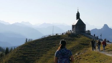 Tegernsee, Almanya - 23 Ekim 2019: Turistlerin yürüdüğü Bavyera Alpleri 'nin güzel yamacındaki eski kilise