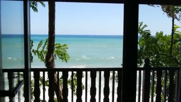 Kilátás az erkélyről a gyönyörű trikolor tenger különböző árnyalatú türkiz kék és sötétzöld hullámok és fehér hab rajta — Stock videók