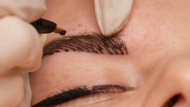 Mikropatenli kaş dövmesi, kalıcı makyaj. Eldivenlerde uzman, özel bir iğne kullanarak, cilde pigmenti enjekte eder ve kaş boyalarını saç tekniği ile lekeler, onları doğal, yakın çekim görüntü yapar.